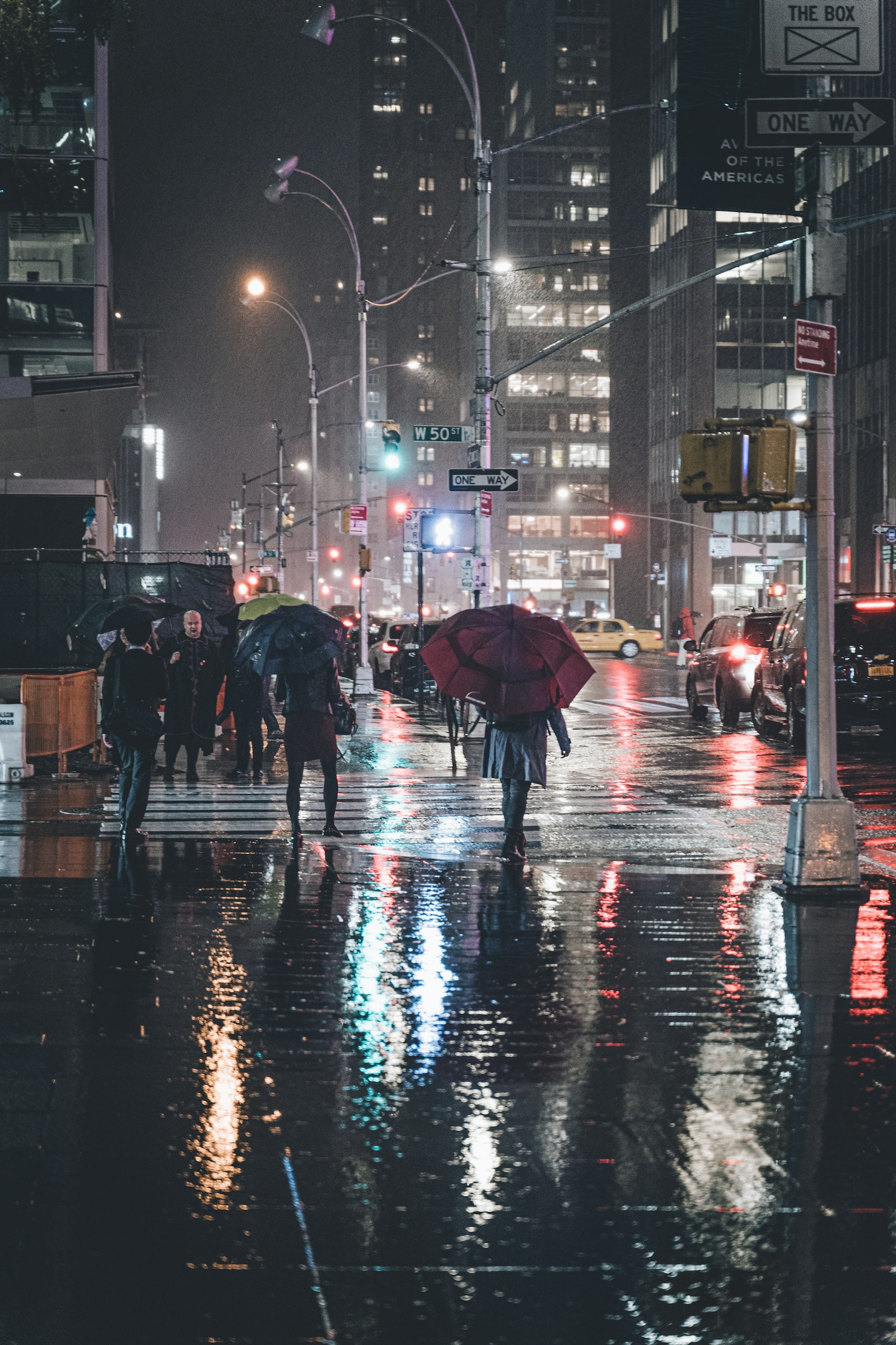 Umbrellas and city lights reflected on a rainy Sixth Avenue in Manhattan
